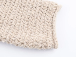Close-up of thick beige knit texture on oversized hoodie sweater with soft wool finish