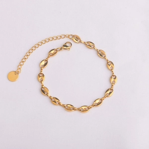 Macro shot of gold coffee bean link bracelet with lobster clasp and round metal tag
