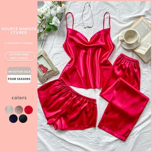Detail of red satin three-piece pajama set including camisole and pants with silk sheen