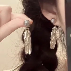 Detail of silver liquid metal drop earrings with spherical studs in a vintage style
