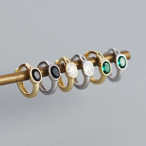 Macro shot of gold and silver hoop earrings with oval black, white, and green zircons