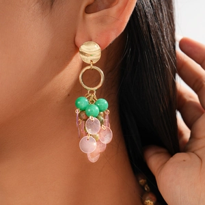 Detail of long drop earrings with green beads and purple discs on a side-profile model
