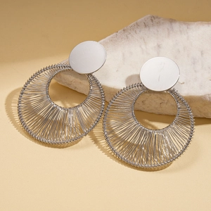 Detail view of silver hollow round earrings featuring textured metallic wire wrapping on stone