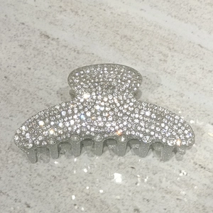 Detailed macro view of large silver shark hair claw clip encrusted with sparkling rhinestones
