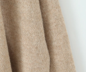 Detailed macro view of soft camel knit wool fabric showing premium fluffy texture and weave