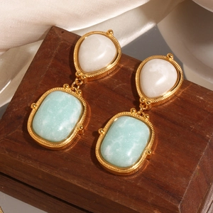 Detailed macro view of 18K gold-plated drop earrings with natural Amazonite on wood