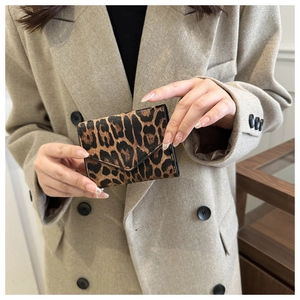 Dettaglio di una mini borsa a busta con stampa leopardata tenuta da una modella alla moda