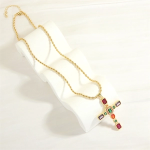 Dettaglio della collana a corda dorata con ciondolo a croce di pietre preziose colorate