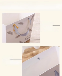 Detail showing the gray ribbon handle and double-layered folded edge of the paper gift bag