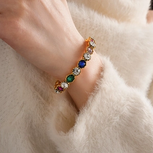 Detail of vintage gold bracelet with colorful oval-cut gemstones on a model's wrist