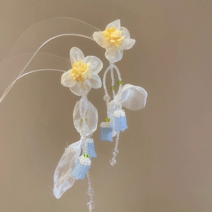 Detail of handmade floral earrings with white and yellow flowers and blue seed bead tassels