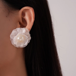 Close-up of white lace flower earrings with pearl center worn by a model
