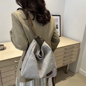 Versatile grey tote bag shown on model in a minimalist home setting with brown straps