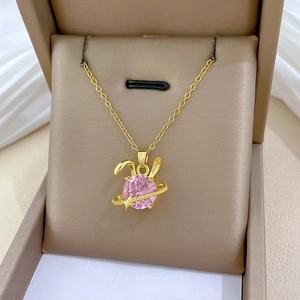 Close-up of golden bunny planet pendant necklace with a sparkling pink gemstone