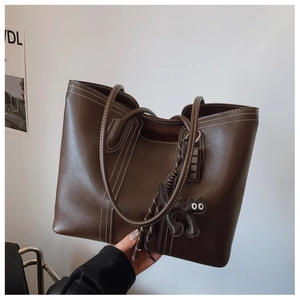 Detail of dark brown tote bag with contrast stitching and a black cat charm accessory