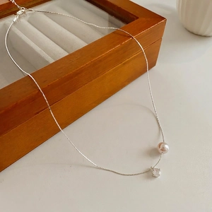 Collier élégant en argent avec pendentif perle et zircon sur une boîte en bois rétro