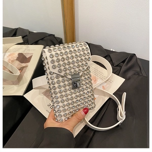 Close-up of white crossbody bag with sparkling rhinestones and metal buckle closure