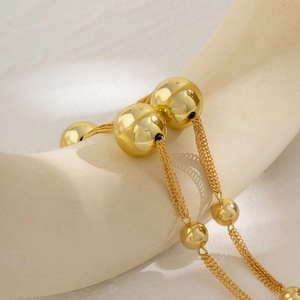 Detail view of large gold metallic beads on a multi-strand choker necklace with polished finish