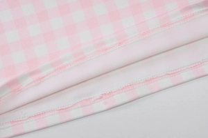 Gros plan sur tissu à carreaux rose montrant les coutures de surjet sur l'ourlet