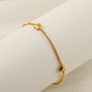 Bracelet chaîne élégant avec breloque cœur doré sur un support à bijoux cylindrique