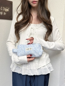 Detail shot of a soft plush makeup bag featuring a blue leopard print with brand label