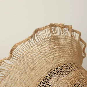 Detailed close-up of handmade raffia sun hat featuring hollow weave and wavy brim design