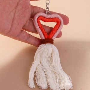 Detail of pink and red hand-woven heart keychain with a long white cotton tassel
