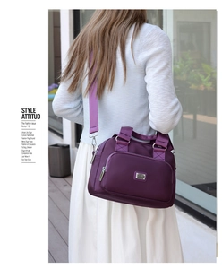 Detail of deep purple waterproof nylon handbag showing long shoulder strap on model