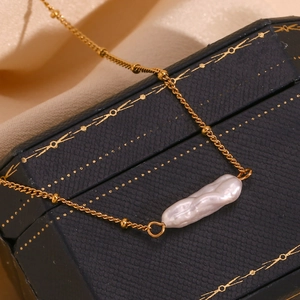 Macro view of a 18K gold-plated necklace with a baroque pearl on a jewelry box