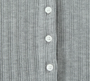 Gros plan sur la maille et les boutons blancs de la patte de boutonnage de robe polo