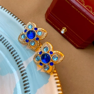 Vintage floral stud earrings with blue crystals and gold plating on a decorative plate