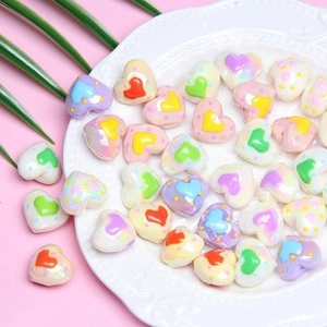 Colorful heart-shaped resin beads in various pastel colors on a white embossed plate