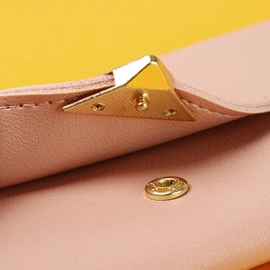 Macro shot of pink leather wallet featuring a gold-tone triangle buckle and snap closure