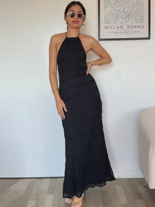 Elegant black halter maxi dress with ruffled layers and tiered texture on a model