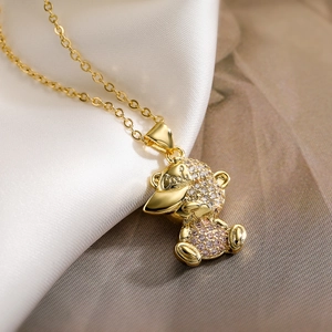 Detail of gold-plated bear pendant with pink zircon crystals on silk background