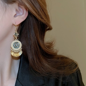 Detailed close-up of Bohemian gold tassel earrings with gemstones worn by a model