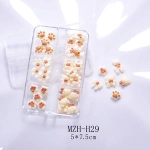 Detail of DIY nail art charms with bear, paw, and bow shapes in a transparent organizer box