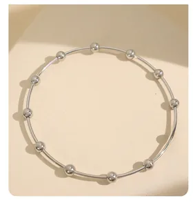 Detail of silver beaded stainless steel bangle featuring polished metallic finish and texture