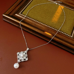 Macro shot of silver pearl necklace with zircon flower pendant on a vintage background