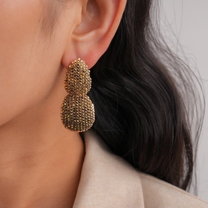 Gros plan de boucles d'oreilles dorées en forme de goutte portées par un mannequin en blazer