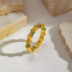 Detail of gold bamboo-shaped ring set with vibrant multi-color gemstones on stone