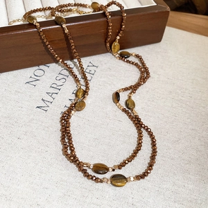 Macro detail of Tiger Eye beaded necklace with metallic facets on vintage wooden box
