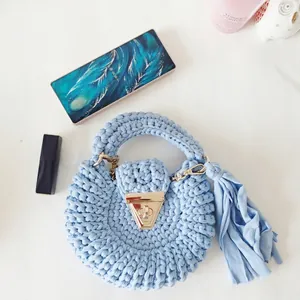 Detail view of light blue bohemian crochet bag with tassel and gold metal clasp