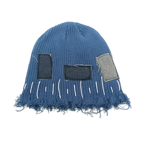 Detailaufnahme der blauen Strickmütze mit Denim-Patches und weißen Kontrastnähten