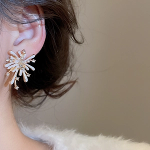 Close-up of elegant firework stud earring with gold base and white enamel on model