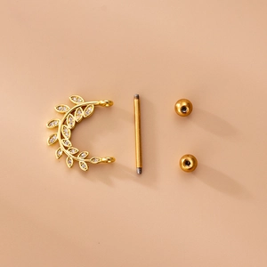 Golden stainless steel leaf nipple ring set with zircon inlay on a beige background