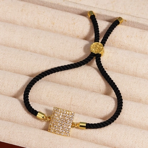 Detail of adjustable black cord bracelet featuring a square gold pendant with cubic zirconia