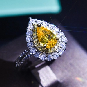 Macro shot of a luxury pear-cut yellow gemstone ring with a double diamond halo setting