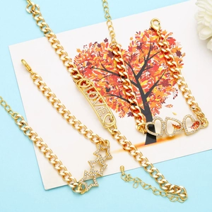 Detailed view of gold chain bracelets with crystal heart and star charms on blue background
