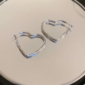 Detailed view of silver heart-shaped hoop earrings with a sleek mirror reflection